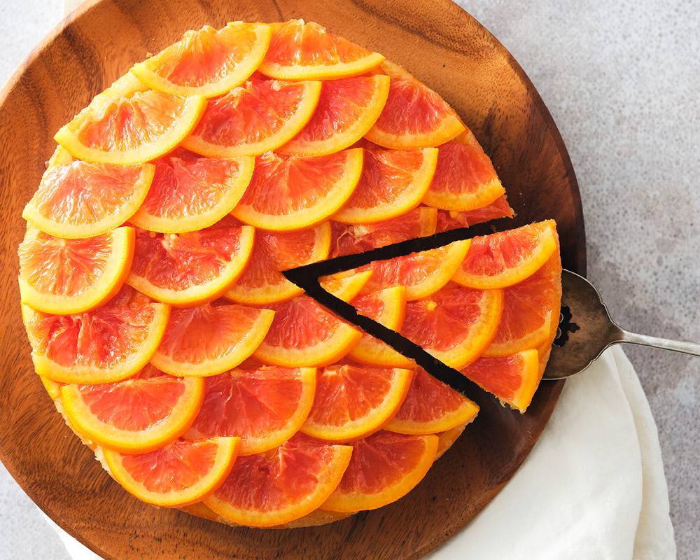 Cara Cara Tahini Upside Down Cake sliced on a wooden serving tray