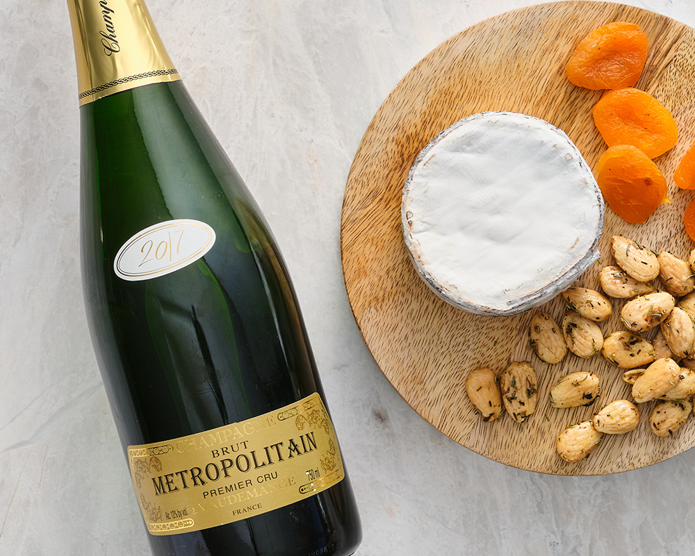 Harbison Cheese next to dried fruit and nuts on wodden board with Metropolitan Market Metropolitain Champagne