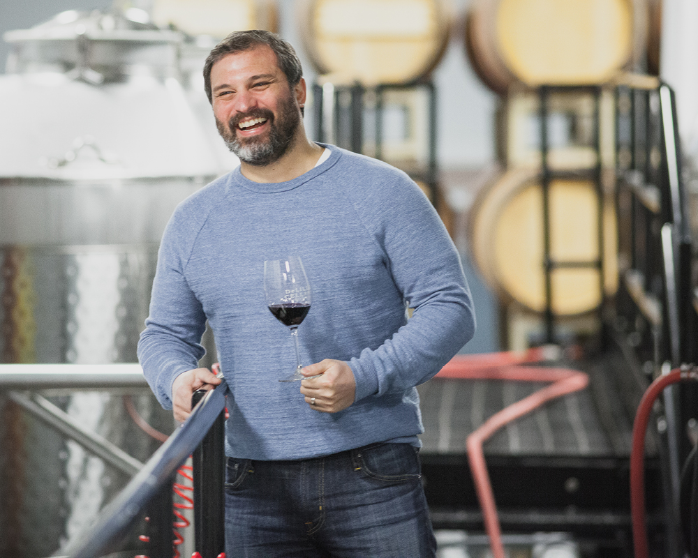 Jason Gorski smiling on staircase of wine making facility