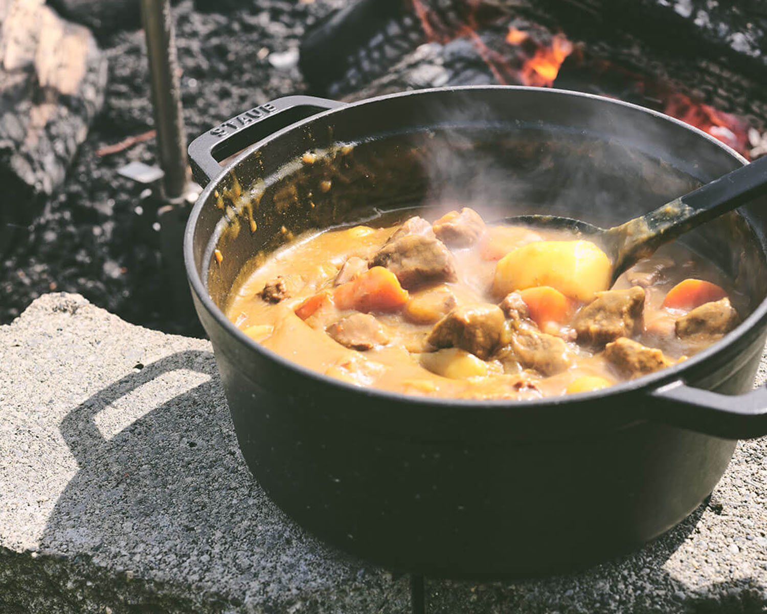 camping cooking a pot of stew