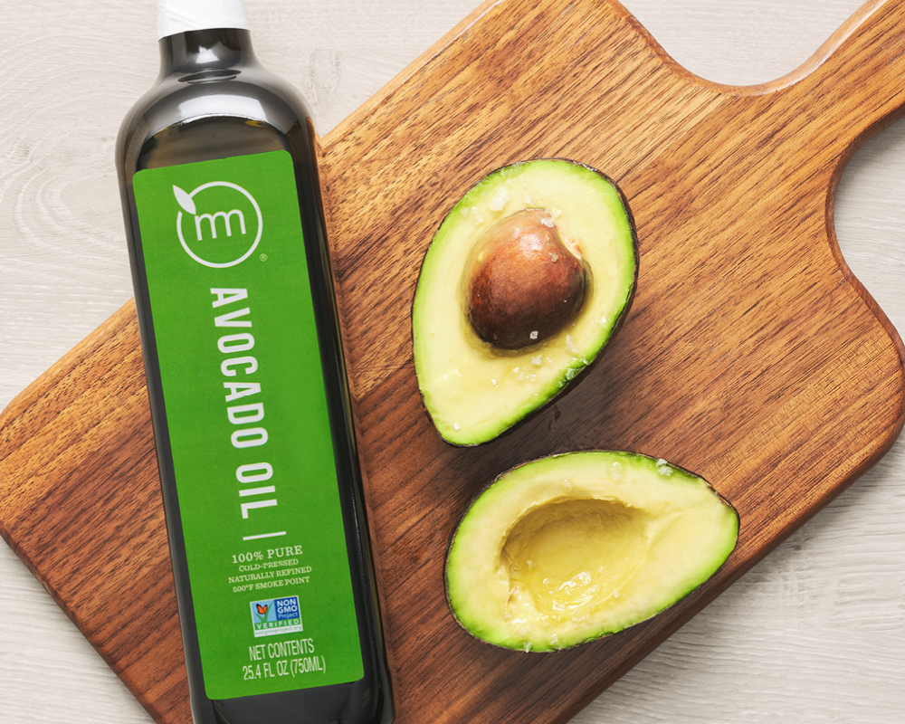 Avocado oil bottle styled with two halves of an avocado