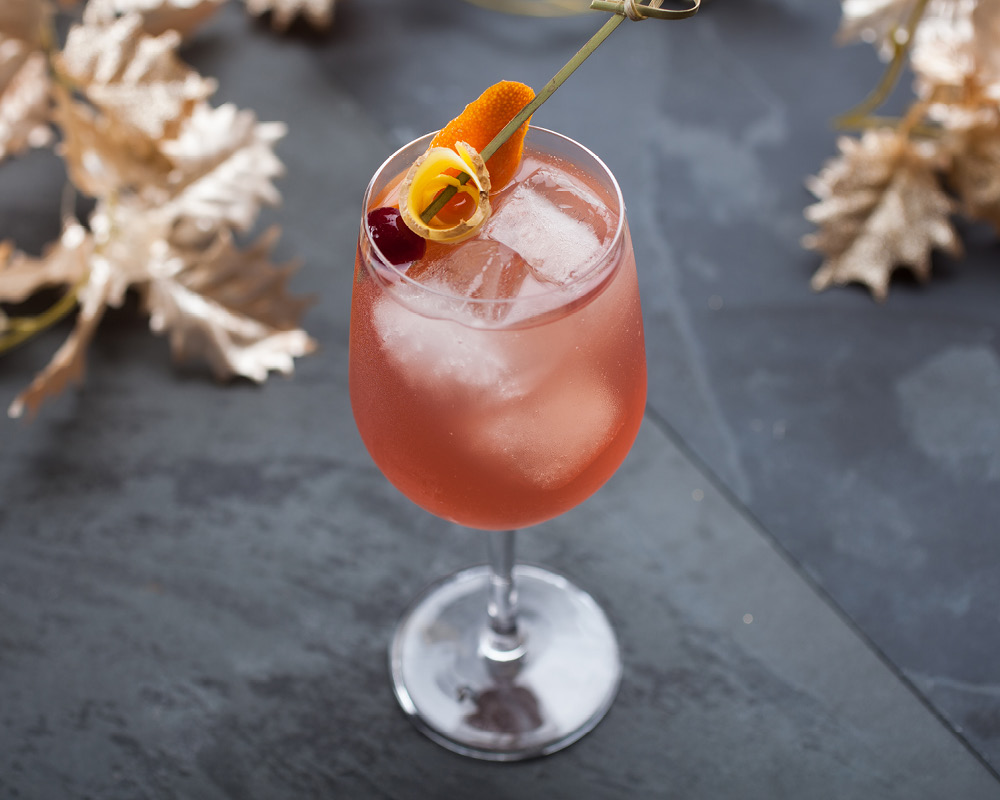 Rum Fizzy Cocktail on a slate gray background with decorative gold leaves