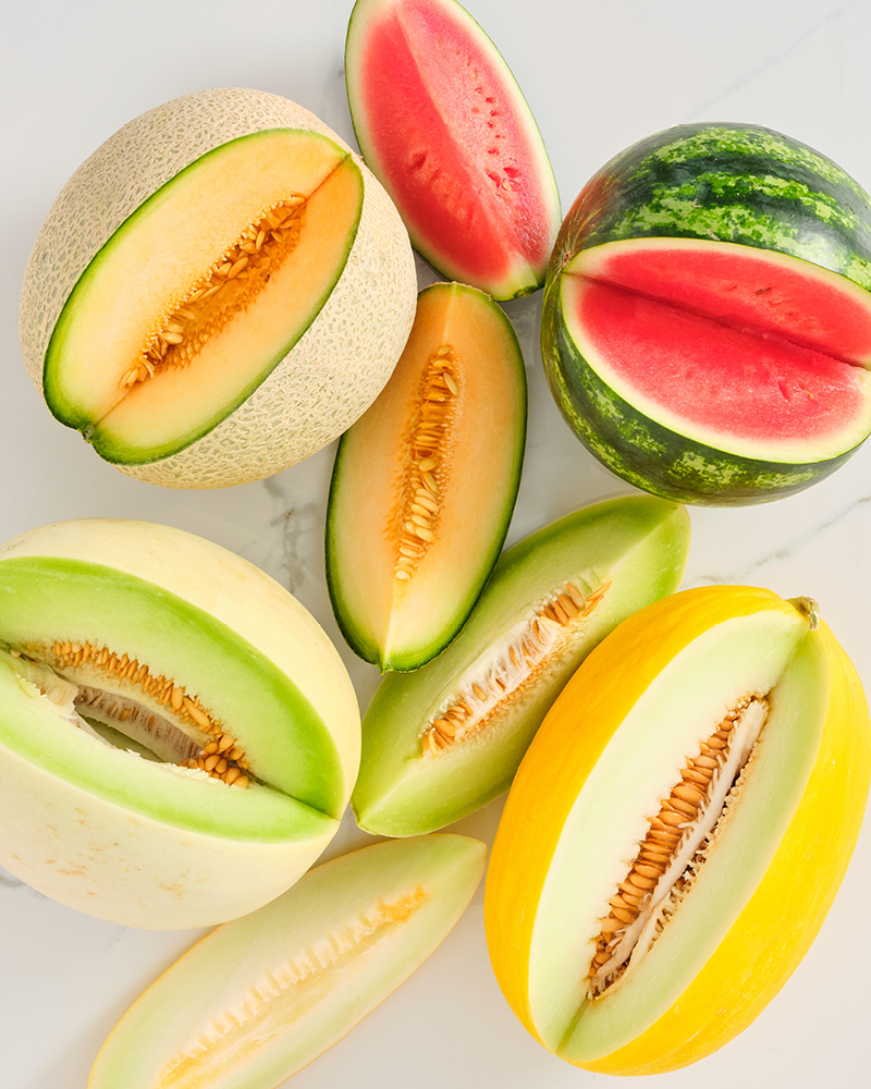 An assortment of melons and cut wedges