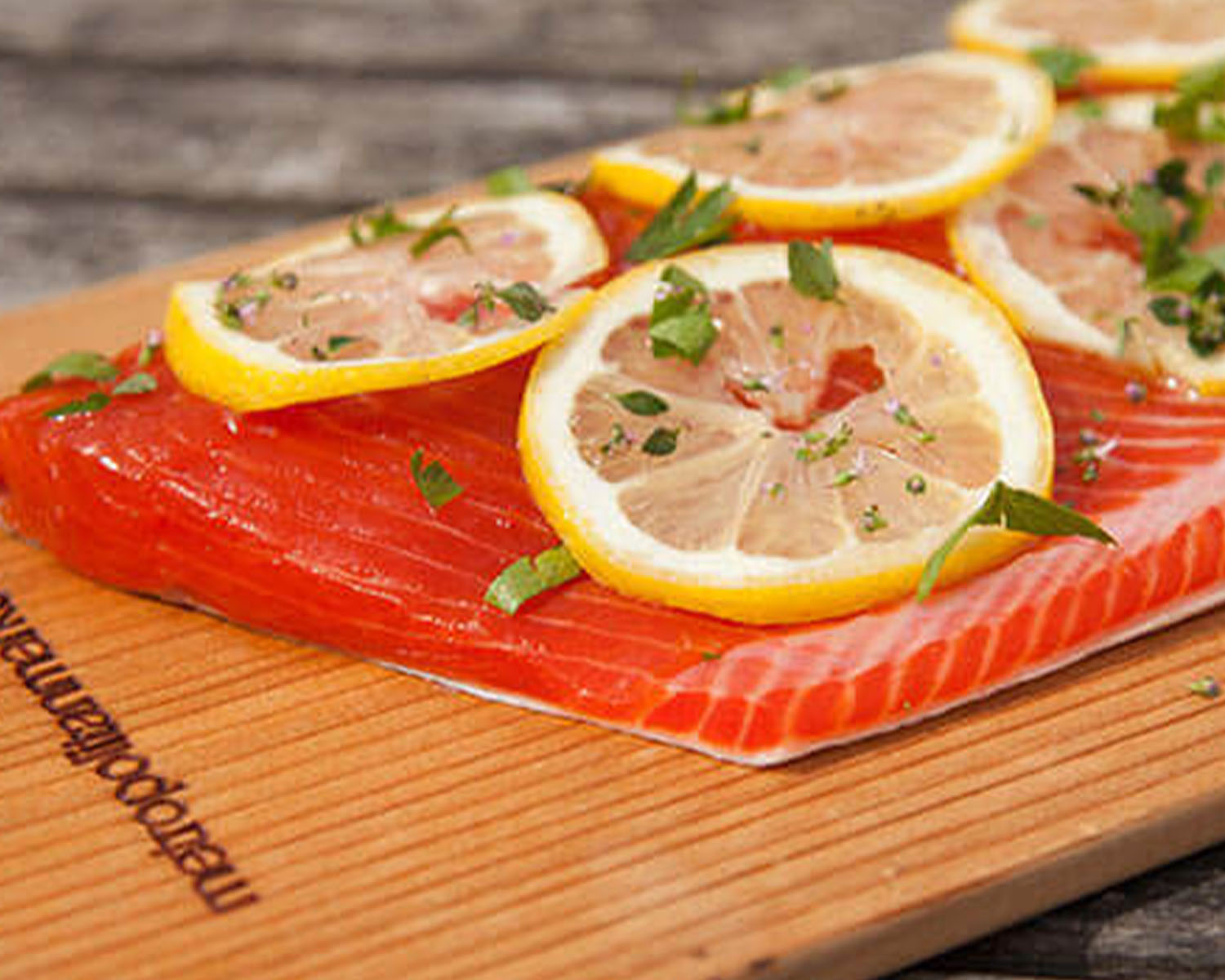 Salmon fillet with lemon slices on a cedar plank.