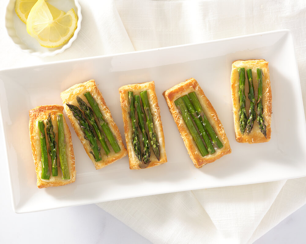 5 small rectangular pastries topped with 3 stalks thin asparagus each