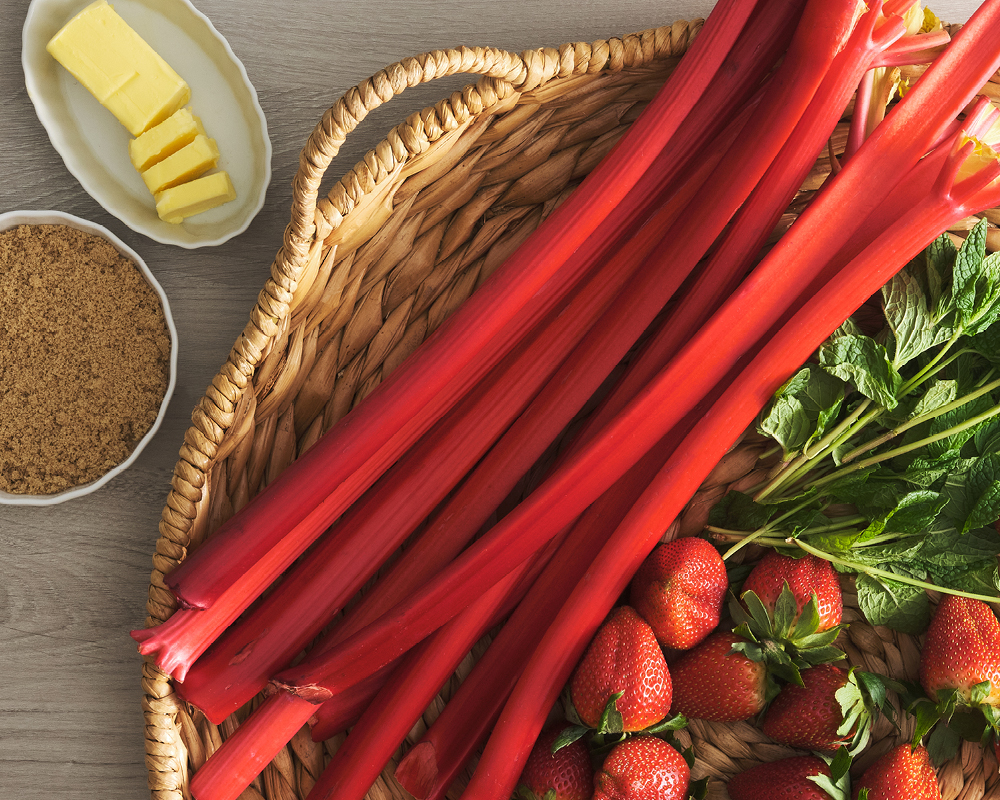 Rhubarb in farmer's market basket with strawberries, mint, butter, and sugar