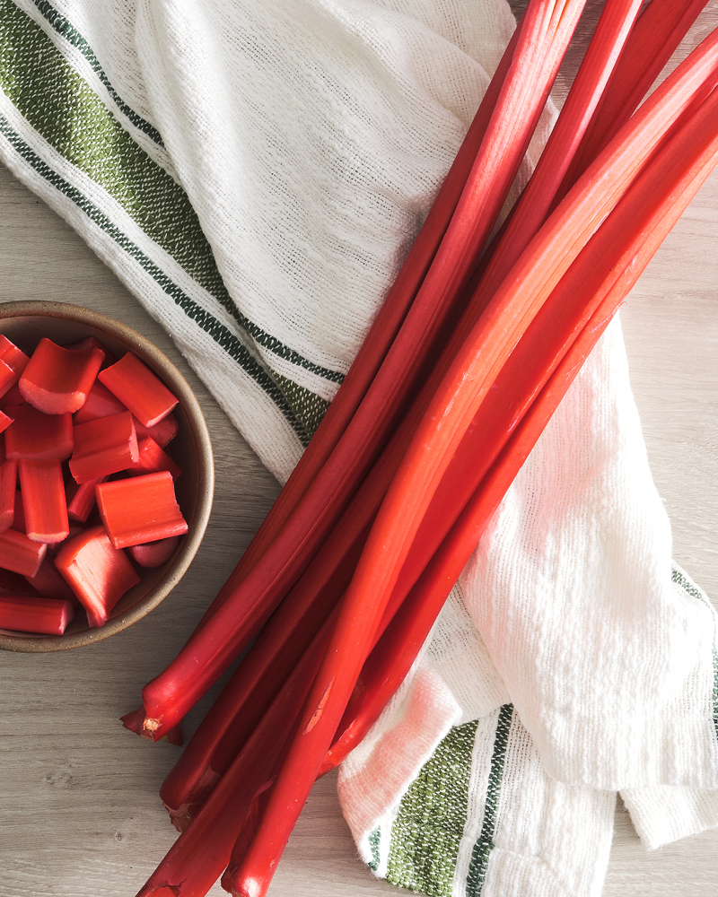 Rhubarb stalks on napkin with chopped pieces in bowl