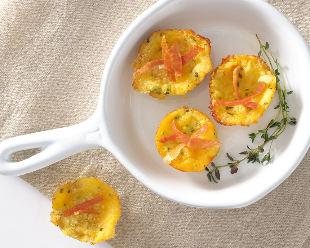 small white pan with 3 potato cups topped with strips of prosciutto and garnished with thyme