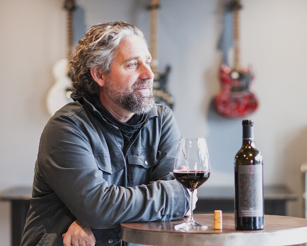Chris Gorman leaning on a table with a glass of wine