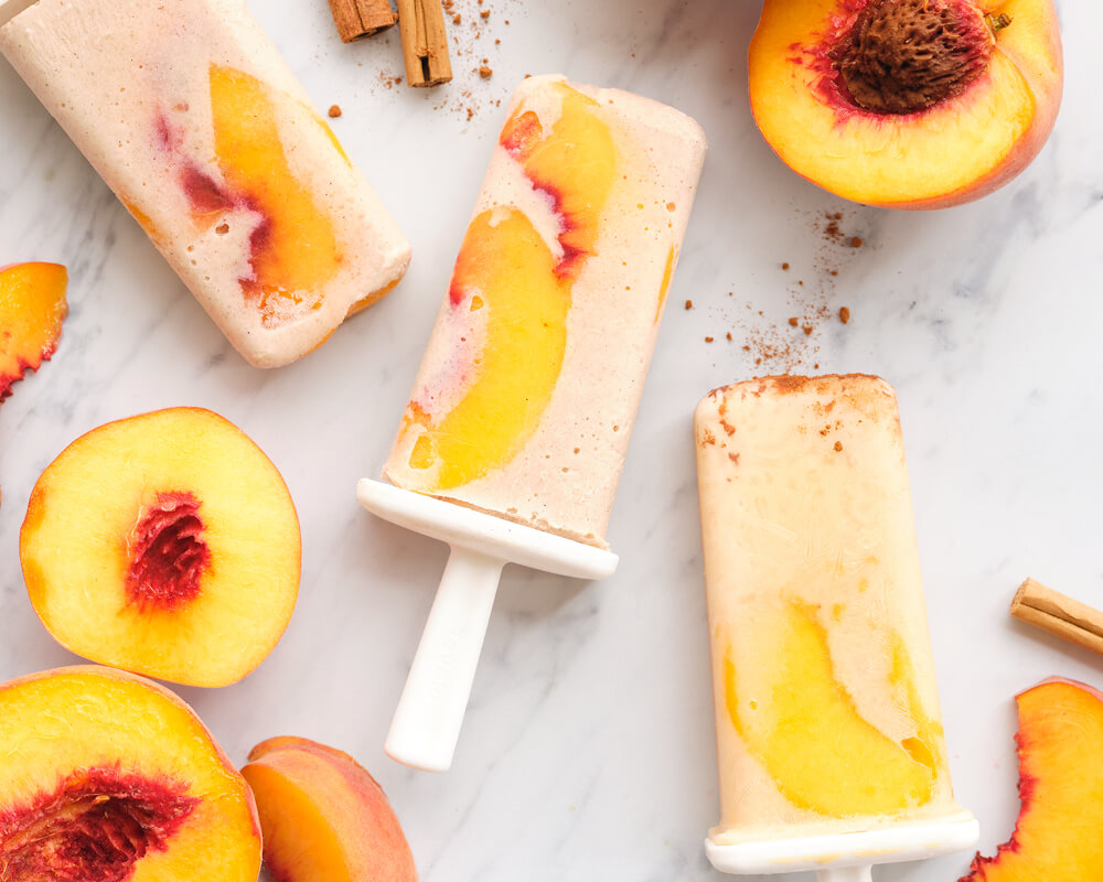 peach popsicles with peach slices and cinnamon on a white background